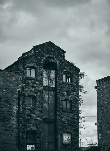 bewachsenes altes Backstein Speicherhaus in Liverpool vor grauer Wolkenstimmung, umgesetzt in schwarzweiß