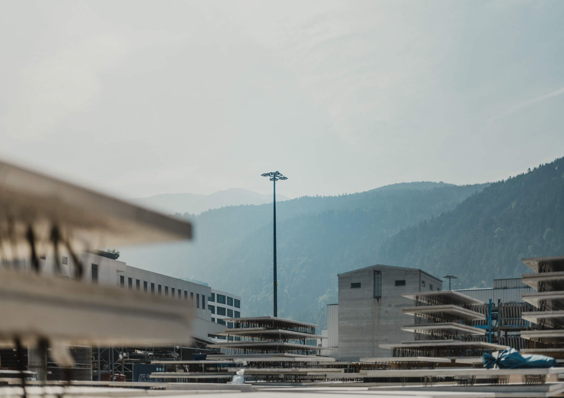 Industrieanlage mit moderner Lichtanlage & Gebäuden und Bergkulisse im Hintergrund.