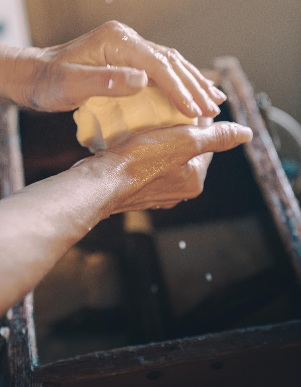 Hände beim Formen von frischer Butter über einem Holzfass