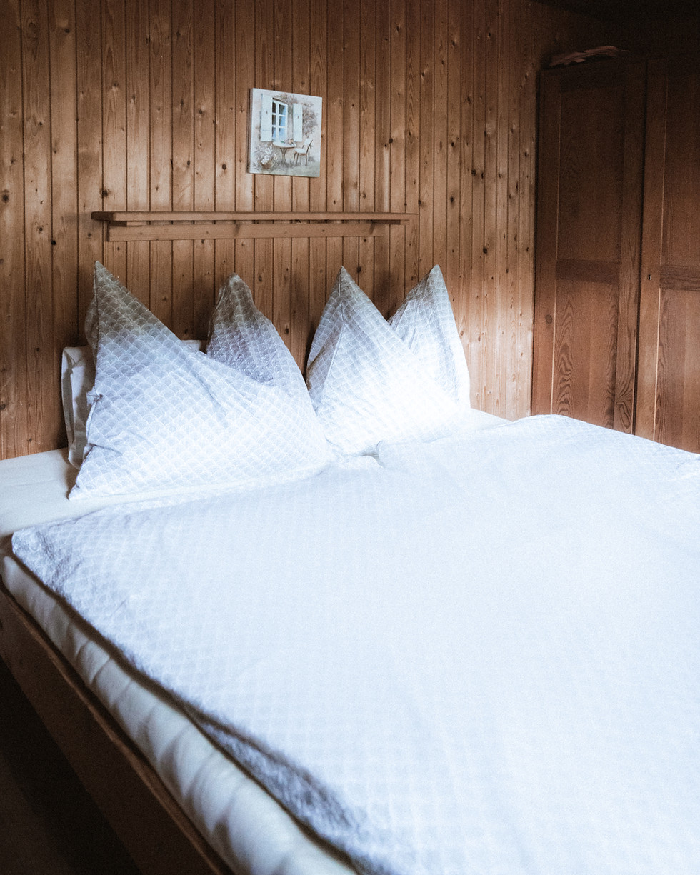 Gemütliches Doppelbett mit weißer Bettwäsche in Holzdekor-Zimmer.