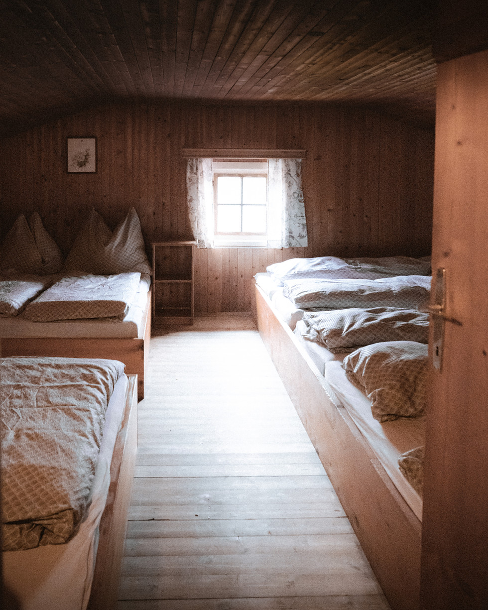 Rustikales Mehrbettzimmer mit Holzverkleidung und Fenster.