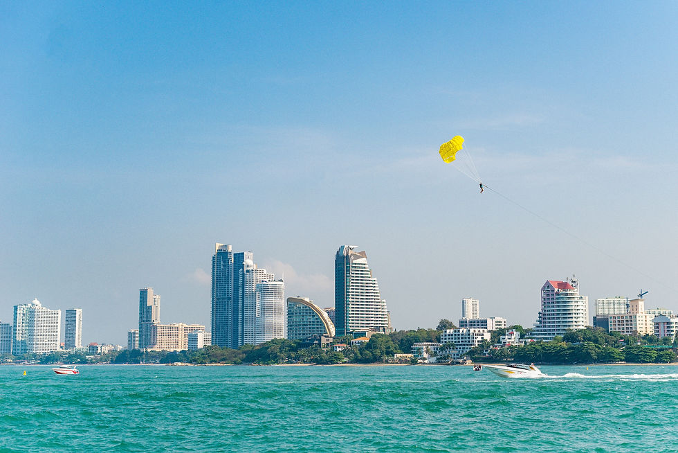 A cityscape by the ocean with a yellow parasail soaring in a clear blue sky, Pattaya, Thai