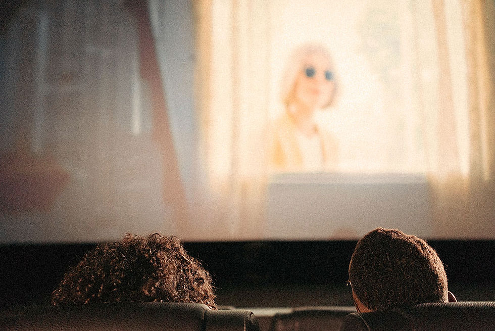 Dos personas ven una película en un cine; en la pantalla, una mujer rubia desenfocada.