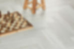 Close-up of Nordikka Scandinavian Birch herringbone LVT flooring – pale grey tones with icy finish