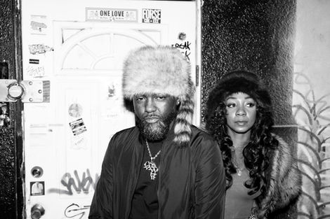 Man in fur hat with tail and woman, black and white