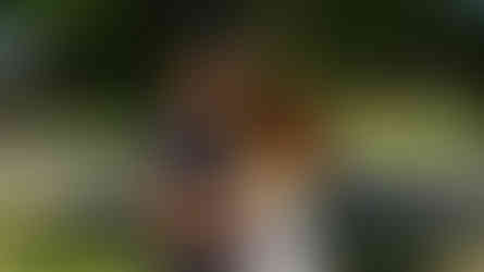 Man with dreadlocks embracing woman in colorful dress.