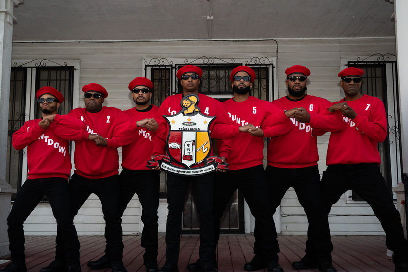 Group of men in red shirts and berets holding a crest