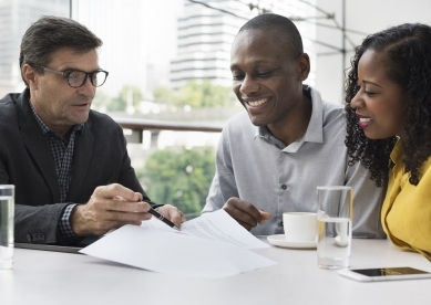 Financial advisor reviewing documents with a smiling couple.