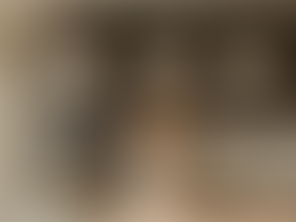 A trio of white, bell-shaped ceramic pendant lights from Naaya Studio hangs over a modern kitchen island, blending with the dark wood cabinets and casting a warm glow.