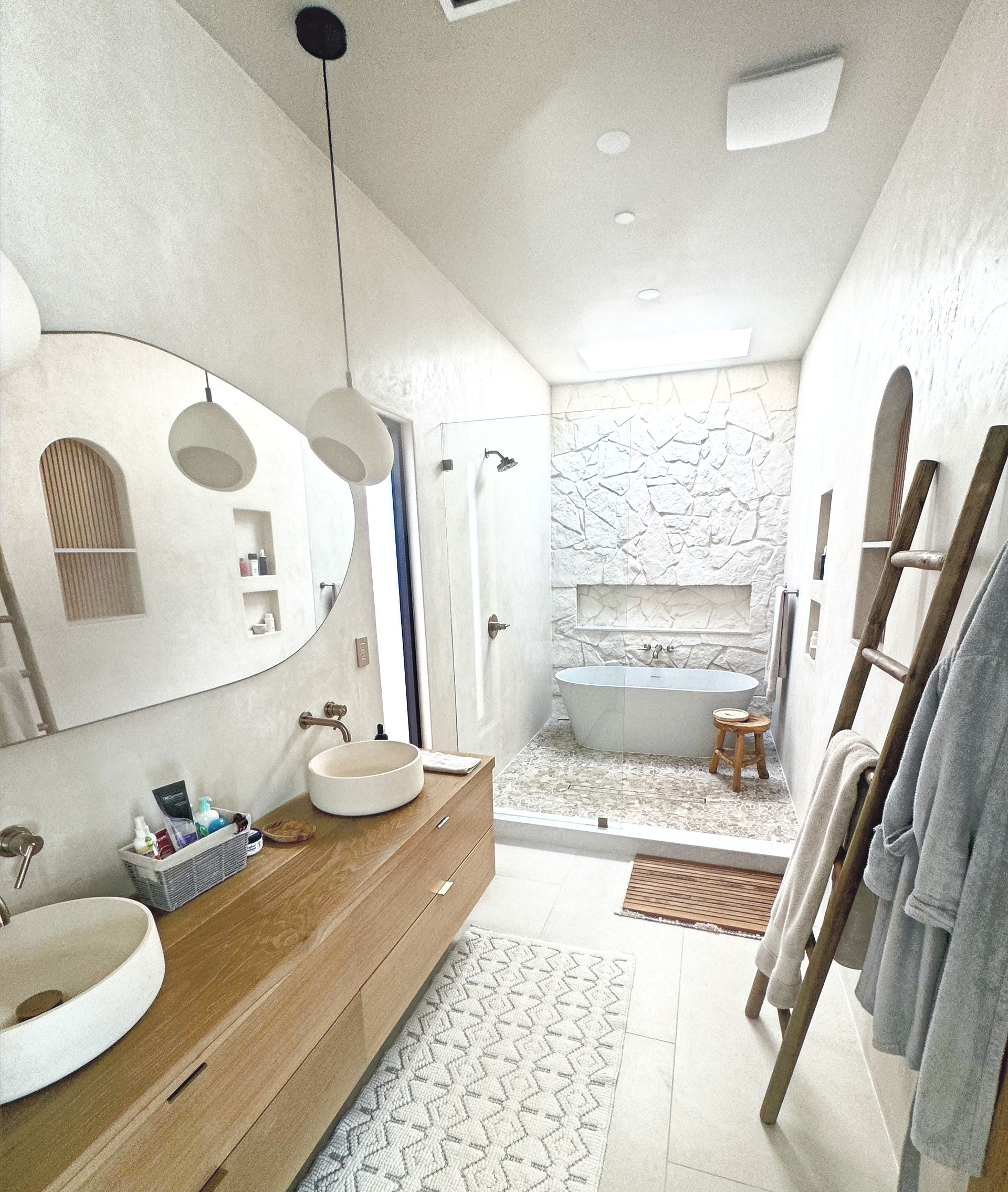 Bright modern bathroom renovation featuring a cluster of three organic white ceramic pendant lights hanging over a double wooden vanity and stone accent wall.