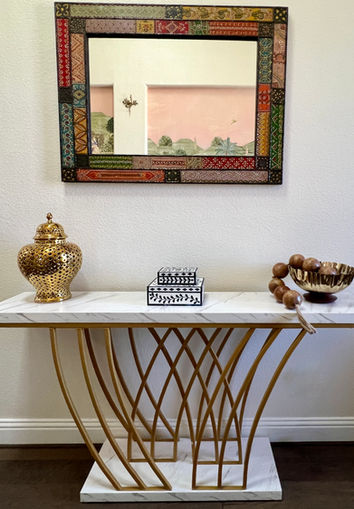 Foyer with marble console table, Indian decorative mirror, brass urn, bone inlay boxes, and gold bowl with wooden beads in Frisco, TX home.