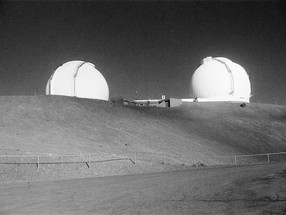 Black and white photograph of an earth mound with two white spherical buildings on top