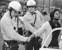 Two white policemen putting handcuffs on a young black woman in Birmingham, Alabama, 1963