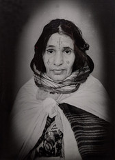 1960s black & white portrait of Amazigh woman with facial tattoos, wearing a scarf, in a photography studio