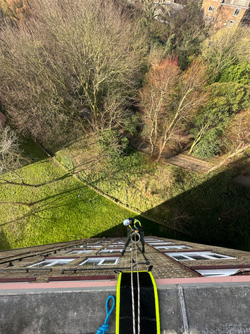 Art of Alpine rope access technician performing building maintenance