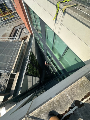 Art of Alpine rope access technician performing building maintenance