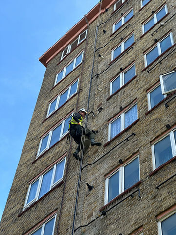 Art of Alpine rope access technician performing building maintenance