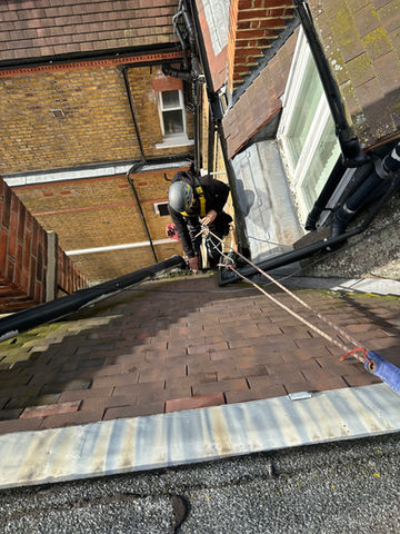 Art of Alpine rope access technician performing building maintenance