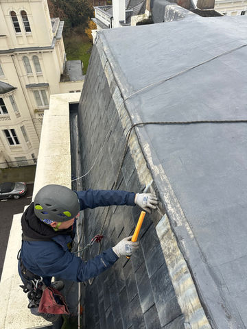 Art of Alpine rope access technician performing building maintenance