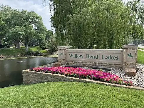 Professional gutter cleaning services at the Willow Bend Lakes neighborhood entrance in Plano, Texas, featuring stone monuments and mature willow trees.