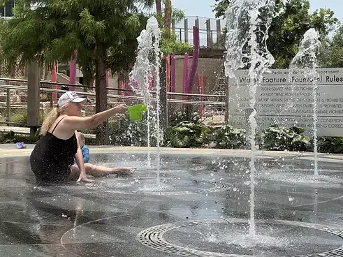 Families enjoying the splash pad at a Frisco, TX Kaleidoscope park on a summer day.
