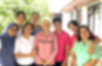 Diverse team of VivoCare caregivers and a resident smiling together outdoors at the VivoCare residence.