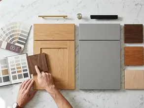 Design consultation with samples of cabinet door styles, wood species, and hardware finishes laid out on a table