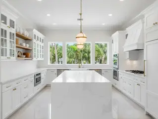 Luxury renovated kitchen in Palm Beach home with white shaker cabinets and a large quartz island