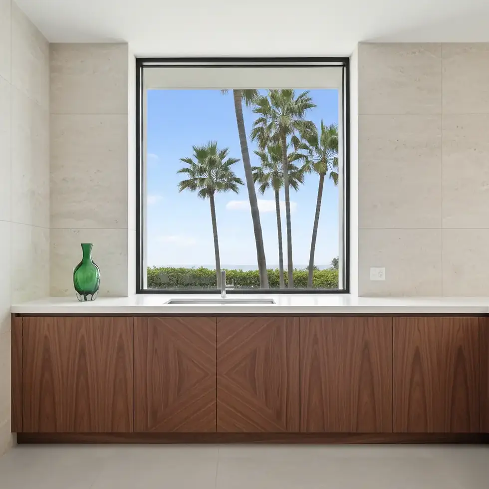 Seamless flat-panel walnut veneer cabinets with book-matched grain pattern in a contemporary coastal kitchen