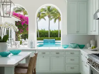 Professionally refinished coastal green kitchen cabinet doors in Palm Beach luxury home with pool view, marble island, and designer details