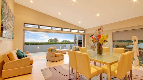 Light-filled dining and living area with large glazing at Riverside House