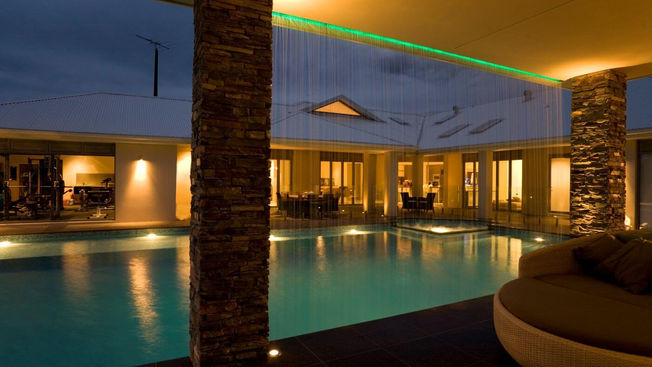 Night view across the swimming pool and alfresco areas at Portrush House