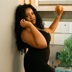 Woman posing for a photography booking session by a window.