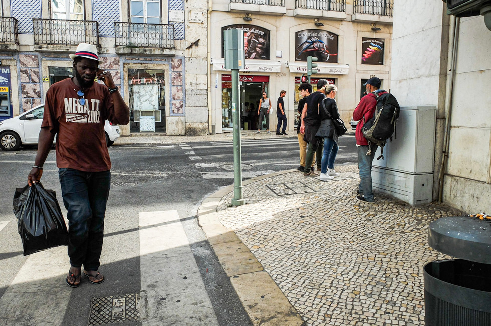 A guy walking down the street holding a bag of rubbish.