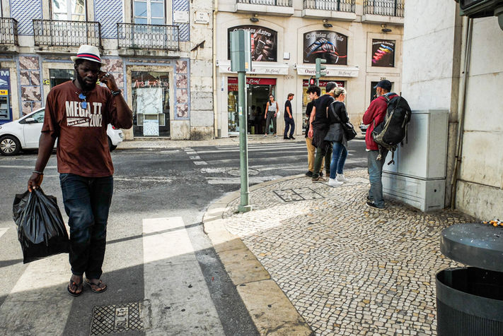 A man wearing a Panama Hat walking the tiled paved street in Lisbon, Portugal