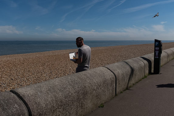 A seagull closes in on a man eating fish and chips on the beach