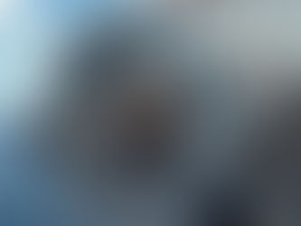 Large industrial turbine against a sea and sky backdrop, featuring metal components and intricate details, with scattered clouds above.