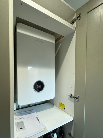 White modern boiler inside a utility closet with instruction papers visible.
Worcester Bosch 4000 model combination boiler, one of many installed by Gibbons Gas.