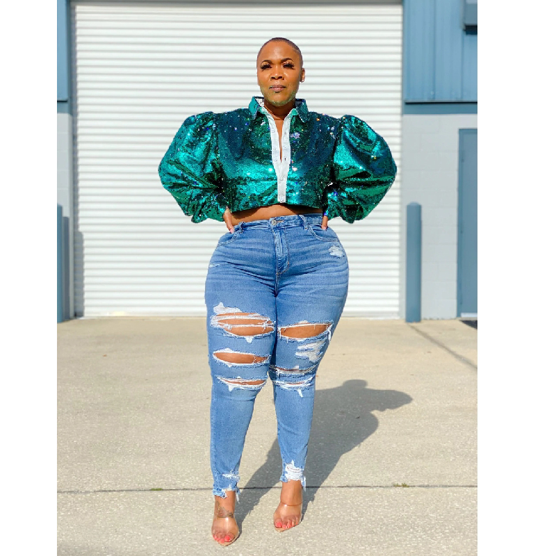 Woman in green sequin top and wide-leg denim trousers