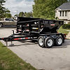 A high-quality, wide-angle photo of a dump trailer in action, like___A 16 ft black dump tr