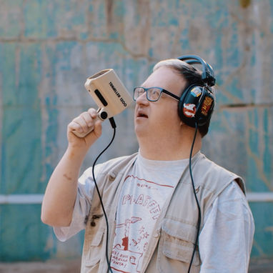 Photo of a boy with down syndrome holding some kind of telecomunication machine, looking up.