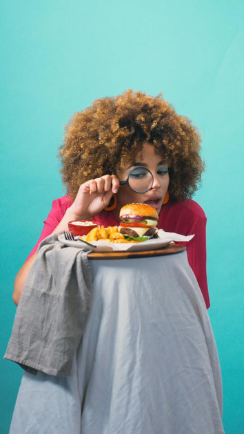 Image of a woman looking with a magnifying glass a burguer.