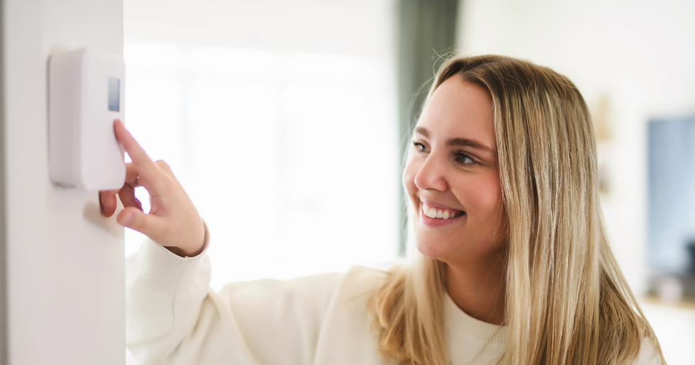 Person in their Greater Victoria home adjusting the thermostat and smiling while saving energy during the BC Hydro Peak Saver winter event.