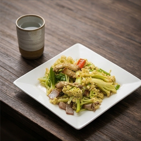Stir-fried cauliflower and pork on a white plate