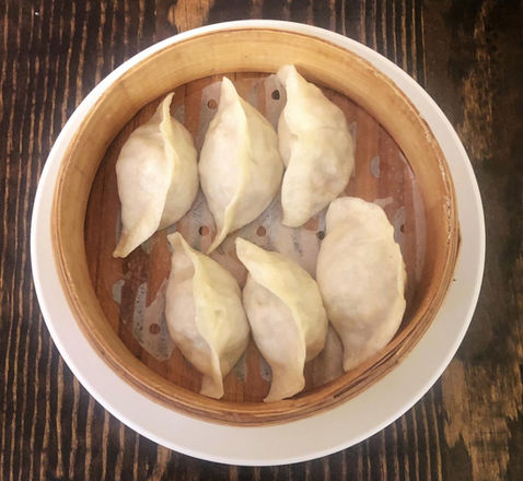 Six dumplings in a bamboo steamer basket