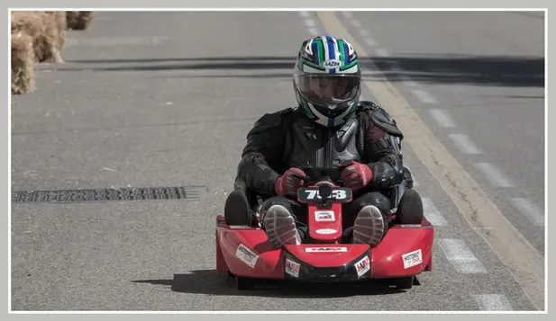 Pilote de karting dans la rue, portant un casque, prêt pour la course.