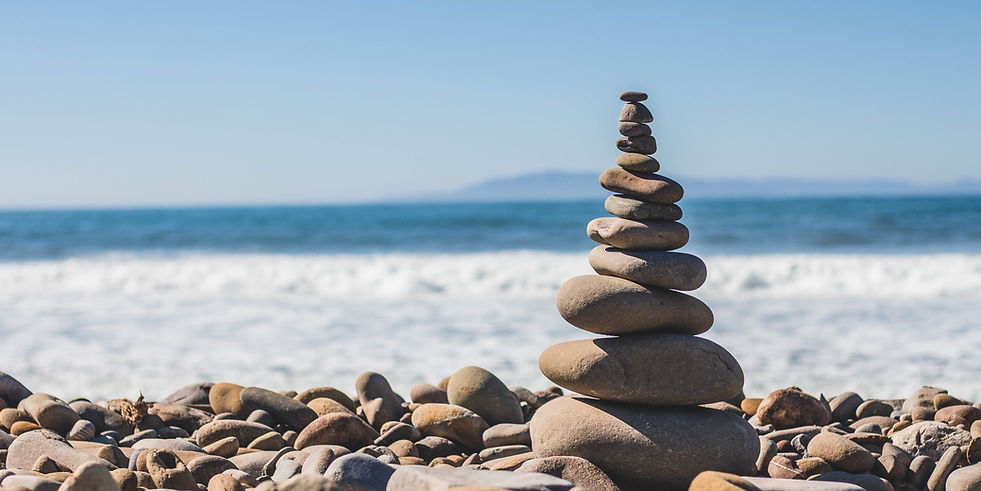 Stacked stones on a beach symbolizing balance, grounding, and holistic cellular wellness.