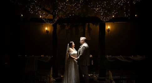 bride and groom under fairy lights with the bride and groom being lit up by a flash