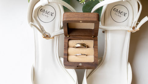 brides shoes, flowers and rings on a flat lay image.
