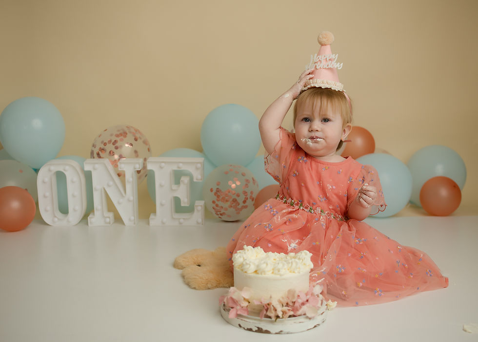 Eye-level view of a soft pastel blanket with balloons and a small cake